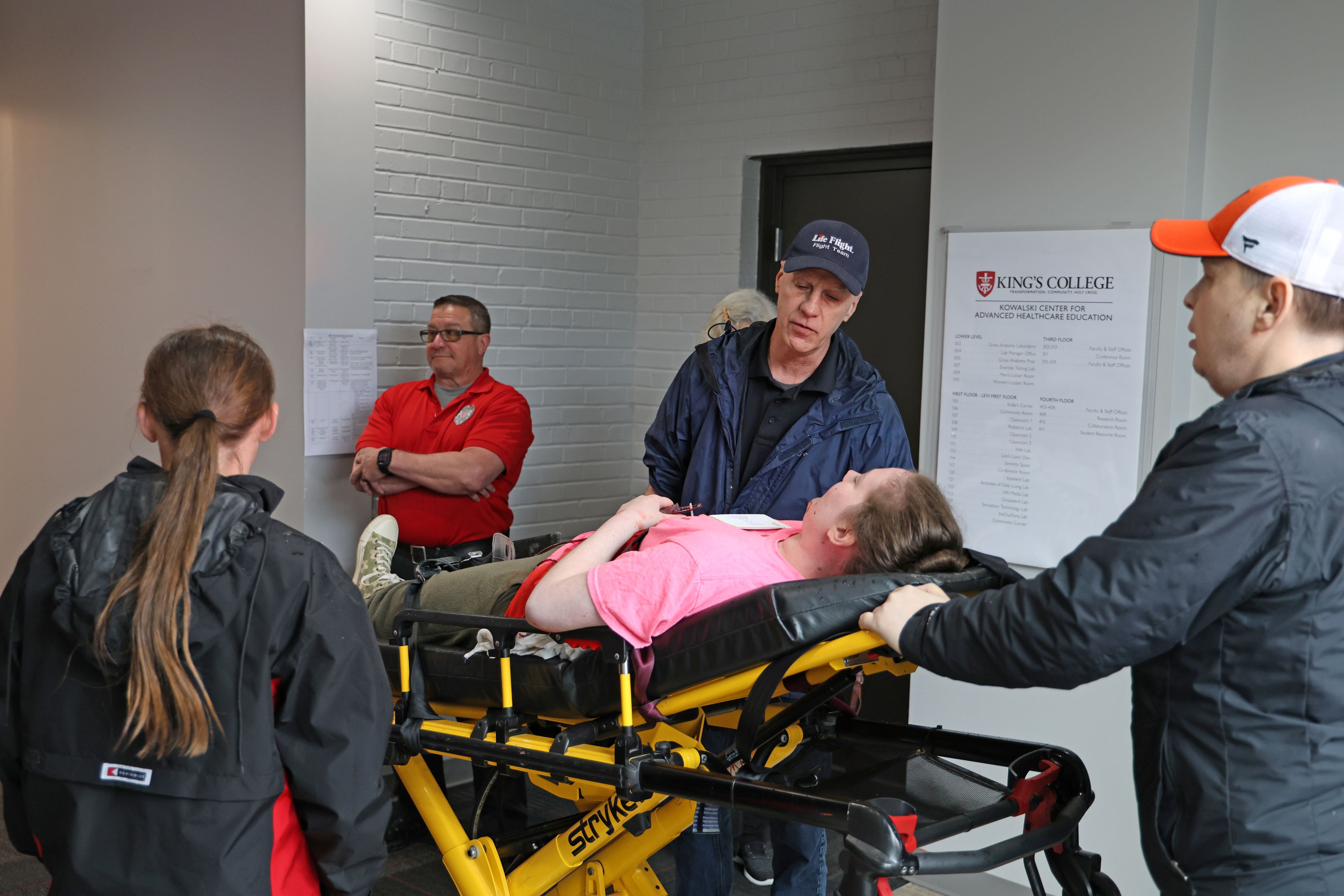 On the stretcher is Gia Cianfichi, a nursing student and simulation actor, with Harley Sullivan, an athletic training student, who takes her to the intake area of the simulation.