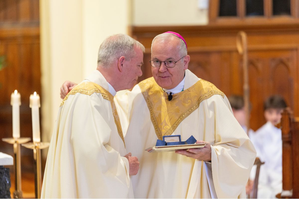 Father Looney hands Bishop Bambera Relic