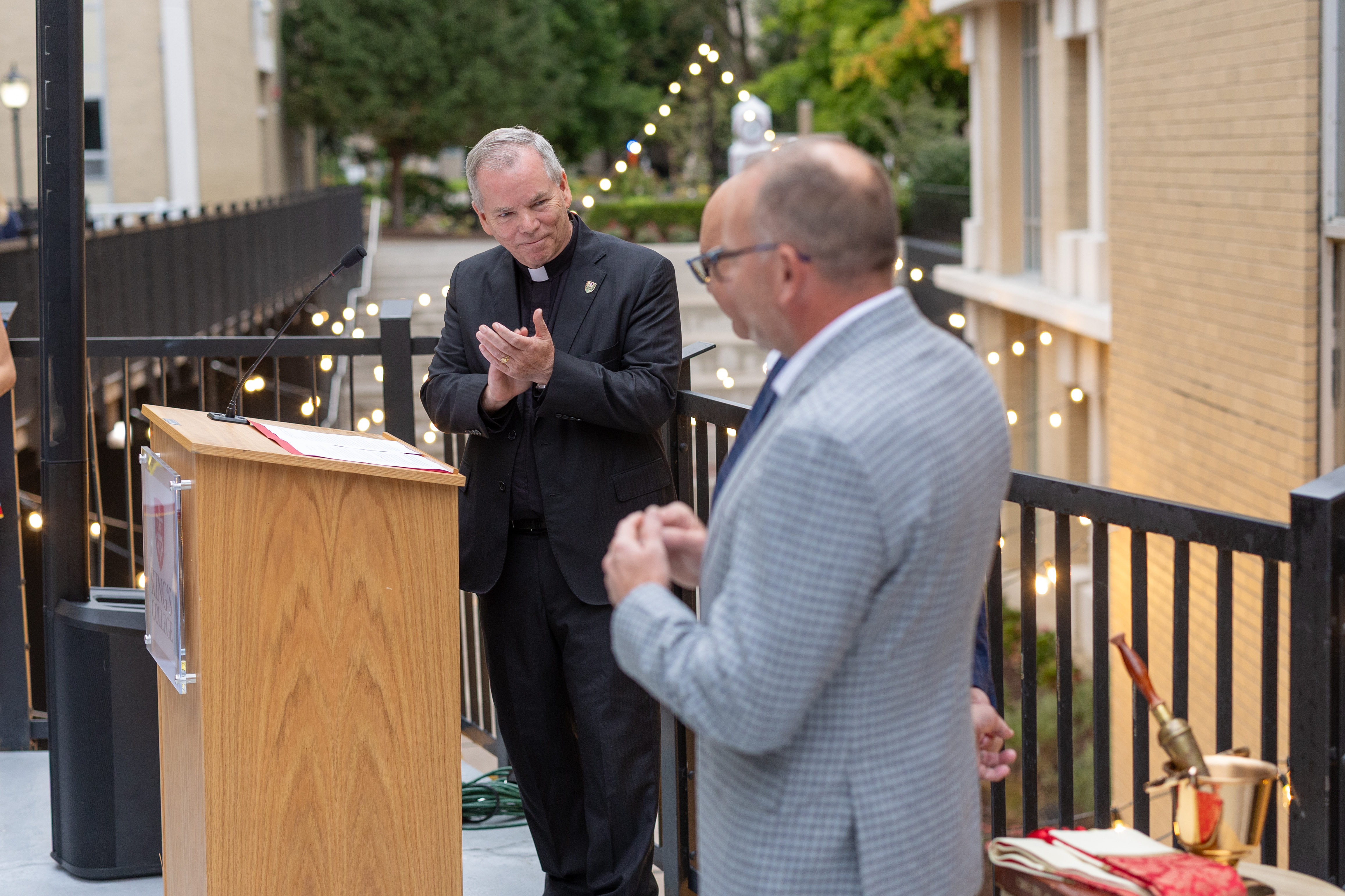 Father Thomas Looney clapping and thanking Mike Molewski and Jimmy Edwards for their $2 million donation