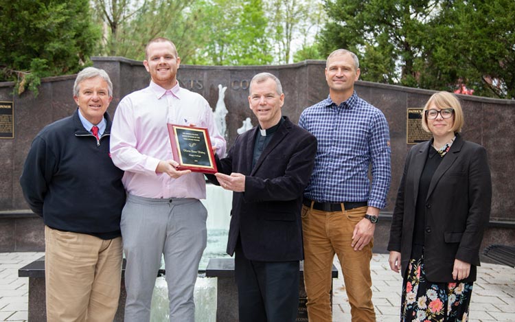 Fr. Looney poses with the award plaque 