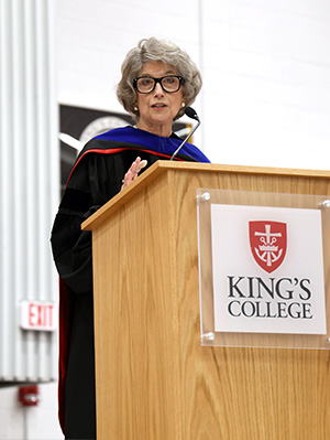 Dr. Kolaowski stands at a podium delivering her speech.