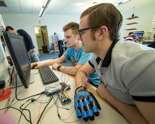 engineering student programs a robotic glove