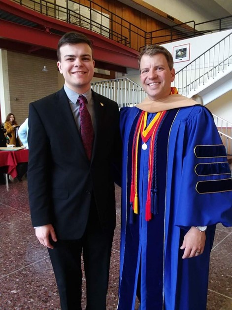 A student poses with a faculty member in professional attire. 