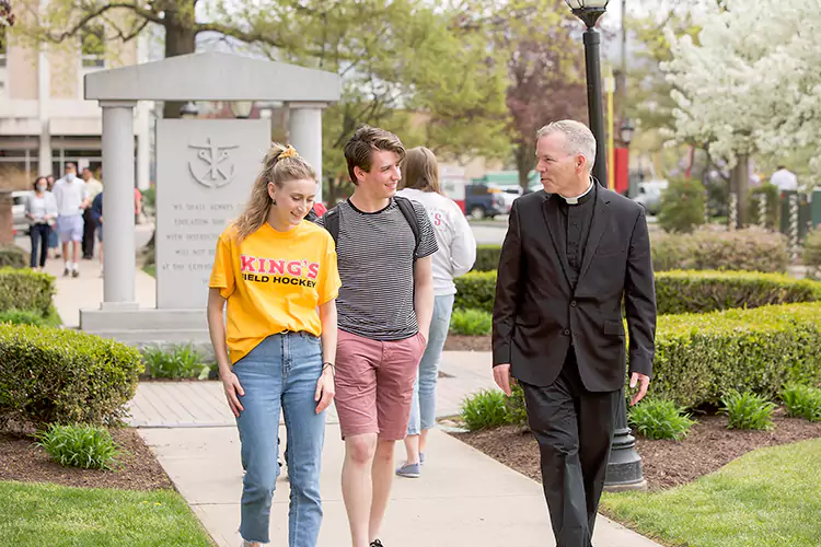 Fr. Tom walking with students in front of the founder's monument.