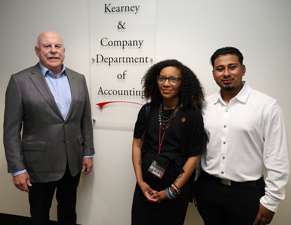 Group photo of Ed Kearney, Deborah Flores, and Henri Avila posing by the sign for the accounting department.