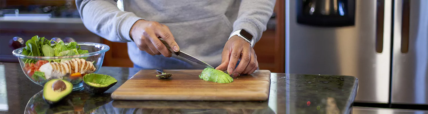 a man making a salad cutting a fresh avacoda on a wood cutting board