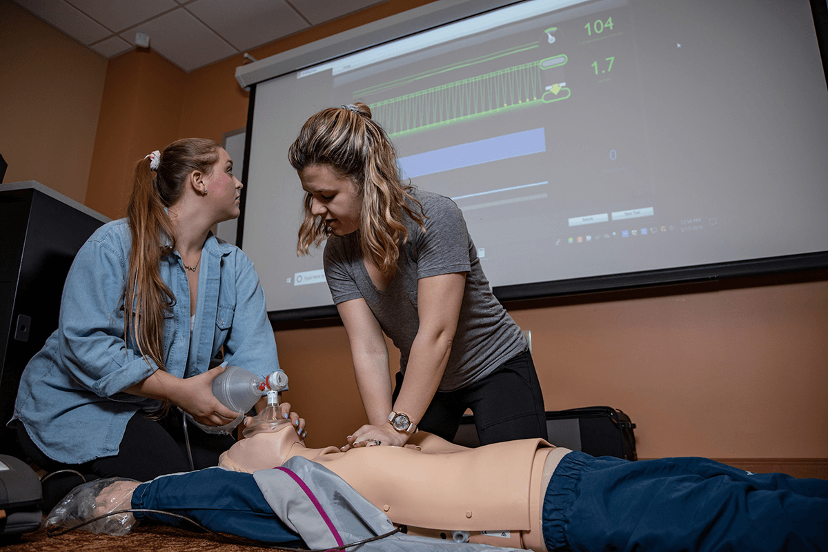 nursing students practice CPR and monitor vitals on a dummy
