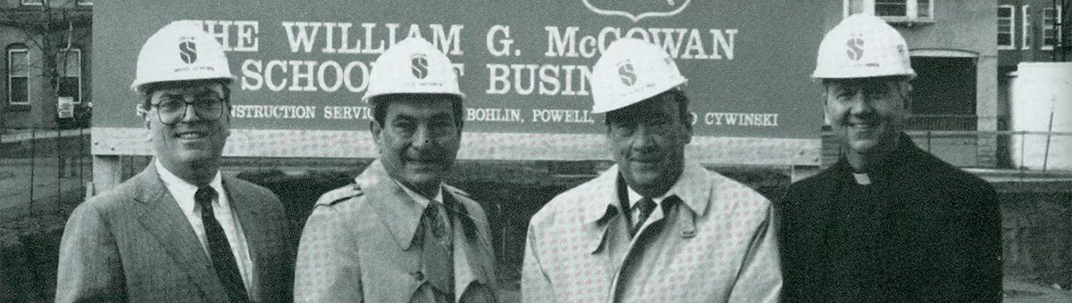 Men in hard hats pose for a photo outside the new McGowan Business School